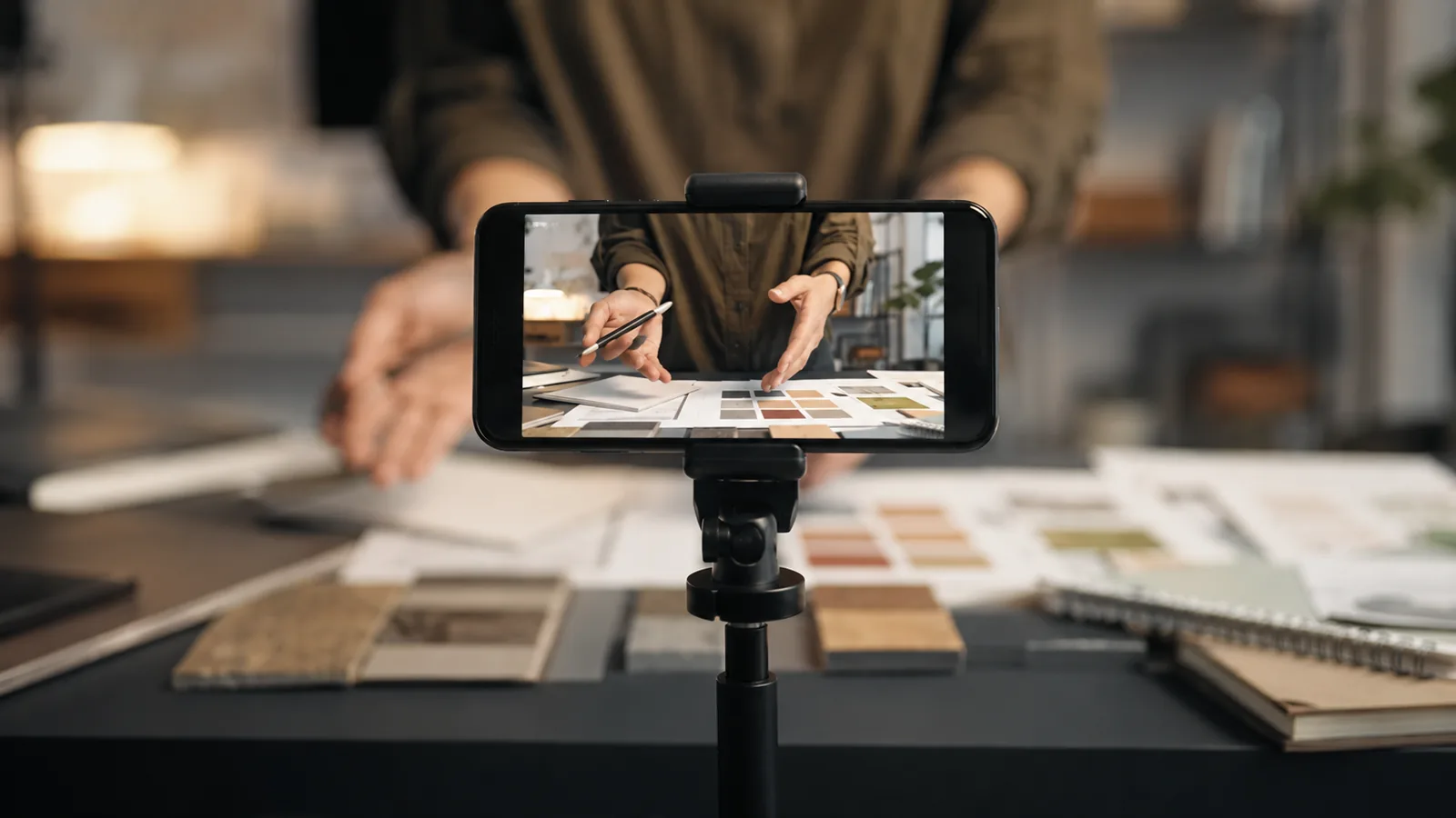 Smartphone filmant les mains d’un professionnel qui montre son travail sans afficher son visage.